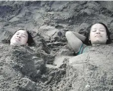  ?? Reuters ?? People with their bodies covered in sand at the beach as they celebrate Easter Sunday in Tanza, Philippine­s, on Sunday. —