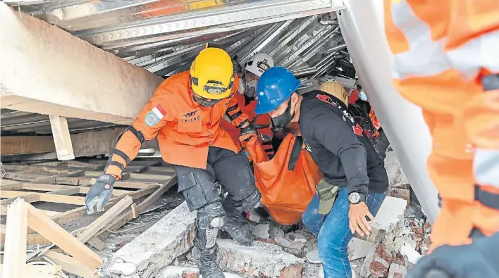  ?? AFP ?? Rescate. Una patrulla de bomberos y sanitarios acarrea el cuerpo de una de las víctimas hallado bajo los escombros de una casa que destruyó el terremoto de 5,6 grados en Cianjur.