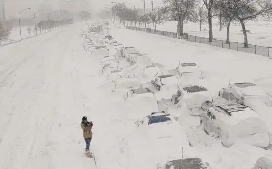  ?? SUN-TIMES FILE ?? A woman takes photos of cars stuck in the northbound lanes of DuSable Lake Shore Drive near North Avenue after they were trapped by snow on Feb. 2, 2011.