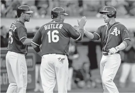  ?? JOSE CARLOS FAJARDO/STAFF PHOTOS ?? Danny Valencia, left, and Billy Butler congratula­te A’s teammate Jake Smolinski, right, after Smolinski’s three-run home run in the second inning Thursday.