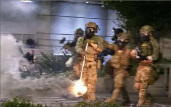  ?? Beth Nakamura/The Oregonian via AP ?? Police and federal agents gather as protesters march during a demonstrat­ion Thursday in Portland, Ore., where agents deployed tear gas and fired “less-lethal” rounds into a crowd.