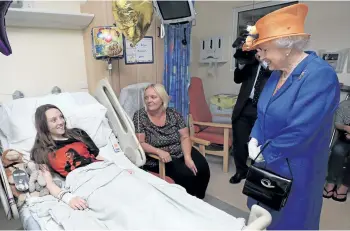  ?? PETER BYRNE/AP ?? Britain’s Queen Elizabeth II, right, speaks to Millie Robson, 15, and her mother, Marie, during a visit to the Royal Manchester Children’s Hospital Thursday in Manchester, England, to meet victims of the terror attack in the city earlier this week and...