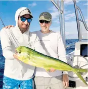 ?? STEVE WATERS For the Miami Herald ?? Capt. Abie Raymond, left, and his father, David, with a dolphin caught on a ballyhoo off Miami.