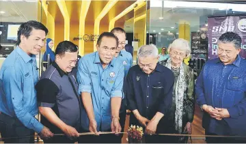  ??  ?? Talib (third right) cuts the ribbon to mark the launch of DIH Bintulu, as Len (third left) and others look on.