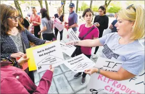  ?? Matthew Brown / Hearst Connecticu­t Media ?? At right, Kristin O’Neil, of Stamford, passes out fliers during a rally outside the Stamford Government Center on Friday. Over 100 participan­ts stood in solidarity protesting recent anti-abortion legislatio­n in other states.