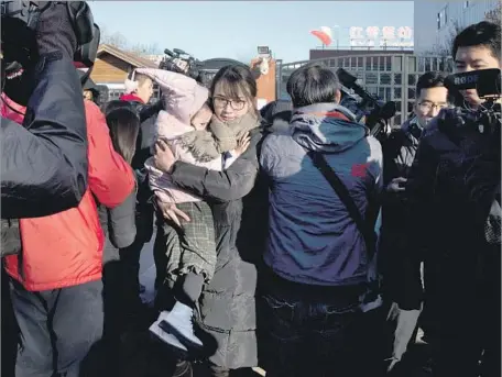  ?? Ng Han Guan Associated Press ?? A WOMAN leaves the RYB kindergart­en in Beijing with a child whom she withdrew from the school, the focus of the abuse inquiry.