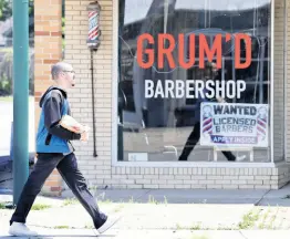  ?? AP ?? A man walks past Grum’D Barbershop’s advertisin­g for barbers on Friday, June 5, 2020, in Euclid, Ohio. The markets reacted positively to unexpected job growth on Friday.