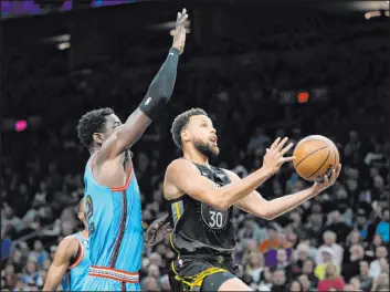  ?? Matt York The Associated Press ?? Warriors guard Stephen Curry goes to the basket past Suns center Deandre Ayton during the first half of Phoenix’s 130-119 victory Wednesday at Footprint Center.