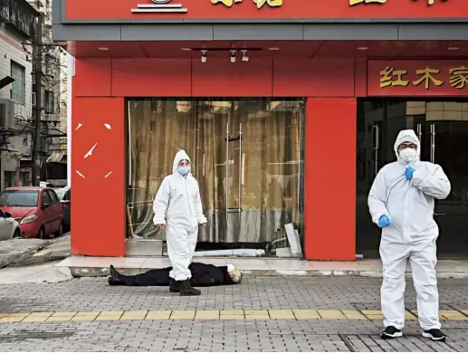 ??  ?? Officials wearing protective clothing investigat­e the body of an elderly man who collapsed and died near a hospital in Wuhan, 30 January 2020