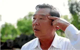  ??  ?? Pham Thanh Cong, above, points at a scar caused by grenade fragments during the My Lai massacre, while fellow survivor Pham Thi Thuan looks at a reconstruc­ted thatched house at the My Lai memorial site.