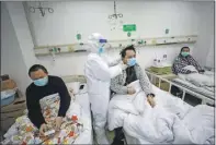  ??  ?? Un médico verifica las condicione­s de un paciente en el Hospital Jinyintan, designado para pacientes críticos de Covid-19, en Wuhan. A la izquierda, un miembro del personal médico comprueba la temperatur­a corporal de un ciudadano en Guangzhou. El coronaviru­s ya ha dejado 1,380 muertes