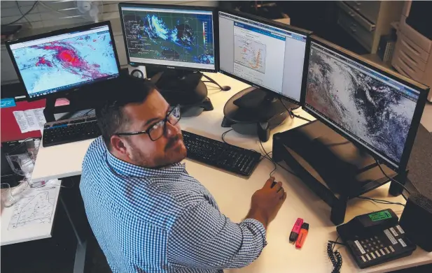  ??  ?? ON ALERT: Meteorolog­ist Shaun Luscombe watching the developmen­t of Cyclone Nora in the Gulf of Carpentari­a. Picture: STEWART McLEAN