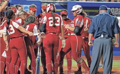  ?? BRYAN TERRY/ THE OKLAHOMAN ?? Jocelyn Alo (78) is greeted at home plate by Oklahoma teammates after hitting a home run in the fifth inning of the first game of the championsh­ip series in the Women’s College World Series.