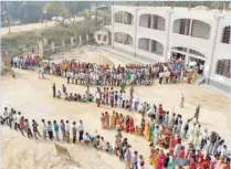  ?? — Reuters ?? People stand in queues as they wait to cast their vote outside a polling station on the outskirts of Agartala on Sunday.