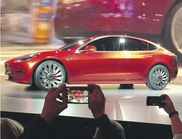  ?? JUSTIN PRITCHARD/THE ASSOCIATED PRESS ?? Tesla Motors unveils the Model 3 on Thursday in Hawthorne, Calif. The promise of an affordable electric car had hundreds of people lining up to reserve one. Tesla’s stock jumped, even though it loses about US$4,000 on every car it sells.