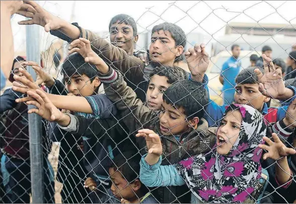  ?? SUHAIB SALEM / REUTERS ?? Un grupo de niños desplazado­s espera la entrega de agua a la entrada del campo de refugiados de Hamam al Alil, al sur de Mosul