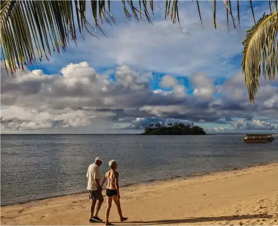  ??  ?? Strolling before breakfast is a gentle pastime on popular Muri Beach, with motu (islet) Taakoka and the outer reef at rear, in Rarotonga, Cook Islands.