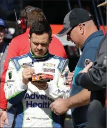  ?? (AP/Terry Renna) ?? Kyle Larson signs an autograph for fans at the Daytona Internatio­nal Speedway in February. Larson, who was suspended from NASCAR in April for using a racial slur, was reinstated by NASCAR and will be eligible to return to competitio­n in 2021