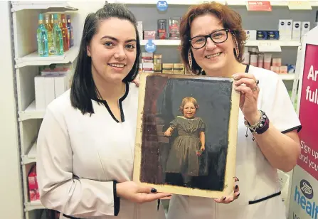  ??  ?? Dispensing assistant Georgette Low (right) and pharmacy technician Jessica Low with the mystery painting.