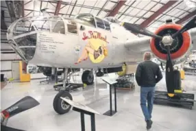  ??  ?? Bill Klaers, president and CEO of the National Museum of World War II Aviation walks toward a North American B-25 Mitchell bomber. Klaers was instrument­al in restoring it. Theb-25 is best known for its role in the 1942 Doolittle Raid on Toyko.