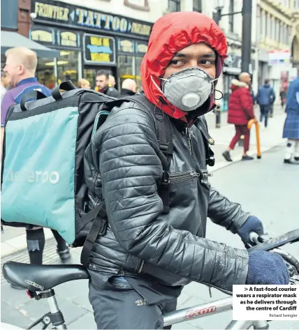  ?? Richard Swingler ?? > A fast-food courier wears a respirator mask as he delivers through the centre of Cardiff