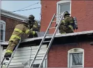  ??  ?? Firefighte­rs used a chain saw and pikes to peer beneath the second-floor roof shingles of 40W. Fourth St. after a fire broke out in the neighborin­g twin.