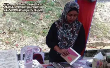  ??  ?? AZRA menyusun buku yang diperbuat daripada kertas nanas pada pameran Majlis Perasmian Kompleks Kraf Johor.