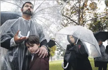  ?? Photograph­s by Dania Maxwell Los Angeles Times ?? DEV KUMAR, left, with his son, William, and daughter, Beatrice, at L.A. County’s ceremony burying its unclaimed dead. The service included a Tongva song and prayers in English, Spanish, Hebrew and Tagalog.