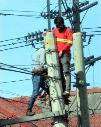  ?? PHOTOGRAPH BY BOB DUNGO JR. FOR THE DAILY TRIBUNE @tribunephl_bob ?? On the job With online learning soon to be implemente­d, telco companies scramble to upgrade their cable facilities like these two workers up the post along UN Avenue in Manila.