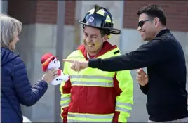  ?? ?? Ciudad Guzman Fire Chief Carlos Chalico, center, is presented with a stuffed dalmatian for the cab of the firetruck. Israel Diaz, right, points out some of the features on the toy.