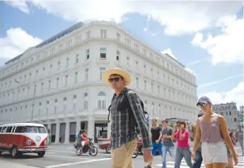  ??  ?? TOURISTS WALK near the Manzana Kempinski Hotel, the first luxury five star plus tourist facility in Cuba, on May 22.