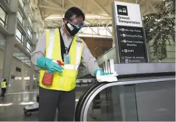  ??  ?? San Francisco Internatio­nal Airport custodial staff member Tony Yee disinfects the escalator handrails at the SFO Internatio­nal Terminal.