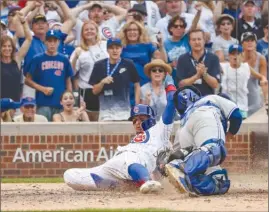  ?? The Associated Press ?? Javier Baez of the Chicago Cubs slides in to score as Toronto Blue Jays catcher Raffy Lopez applies a late tag during the 10th inning of Sunday’s game in Chicago.