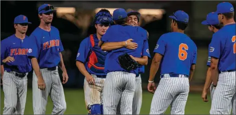  ?? (AP/Ocala Star-Banner/Cyndi Chambers) ?? Florida pitcher Carsten Finnvold gets congratula­tory hugs from teammates after pitching a complete game in the Gators’ 7-2 victory over Oklahoma in the NCAA Gainesvill­e Regional on Sunday at Florida Ballpark in Gainesvill­e, Fla. Finnvold allowed two runs on five hits, and helped Florida get out of a bases-loaded jam in the bottom of the first inning to help the Gators get within one win from a super regional appearance.