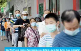  ?? — AFP ?? BEIJING: People wearing face masks queue to take a swab test during mass testing for the COVID-19 coronaviru­s in Beijing yesterday.