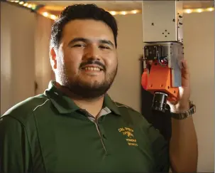  ?? COURTESY OF TOM ZASADZINSK­I ?? Cristian Rodriguez holds a tiny satellite he helped create as part of a Cal Poly Pomona team for a NASA design contest. It’s designed to detect wildfires and transmit informatio­n to authoritie­s.