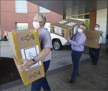  ?? (NWA Democrat-Gazette/Ben Goff) ?? Mike Wilmon (left), Paul Dilbeck and Neil Erter with La-Z-Boy unload boxes of masks Wednesday at Siloam Springs Regional Hospital. La-Z-Boy, which operates a plant in Siloam Springs, donated 10,000 masks to Northwest Health to be used at all five of the system’s hospitals in Northwest Arkansas as well as their covid-19 testing centers.