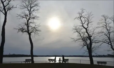  ?? CHRIS CHRISTO — BOSTON HERALD ?? People walk in the veiled sunlight along the coast at David Lynch Park Sunday.