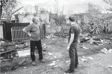  ?? YASUYOSHI CHIBA/GETTY-AFP ?? A father and son stand in the yard of their destroyed home on Thursday in Lyman, Ukraine.