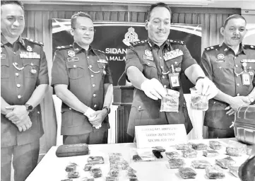  ??  ?? Zaini (second right) showing the 1,158 grams of cannabis. Also seen are Habibi (left) and Ahmad Jawila (right).