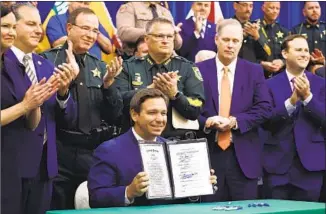  ?? Ricardo Ramirez Buxeda Orlando Sentinel ?? Gov. Ron DeSantis displays the Combating Public Disorder Act at a signing ceremony.