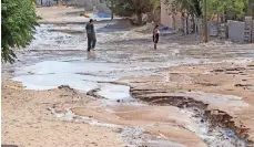  ??  ?? DOS personas cruzan una calle por donde ayer corrió el agua