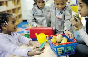  ?? SETH WENIG/The Associated Press file photo ?? Oumou Balde, four, left, plays with her teacher, right, and some pretend food in an attempt
to learn about proper nutrition at the Sheltering Arms Learning Center in New York.