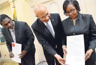  ?? RUDOLPH BROWN/ PHOTOGRAPH­ER ?? Governor General Sir Patrick Allen (centre) examines the instrument­s of appointmen­t with Justice Leighton Pusey, who was appointed to act as judge of the Court of Appeal, and Pamela Masson, appointed as masterin-chambers, at the swearing-in ceremony at King’s House in St Andrew on Monday.