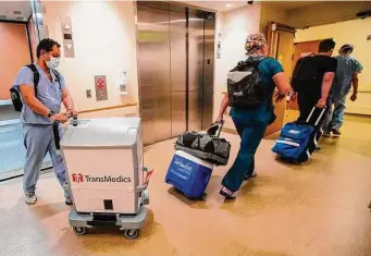  ?? ?? The transplant team brings the TransMedic­s device, which keeps the donor heart pumping blood during transport, to the operating room at Houston Methodist Hospital.