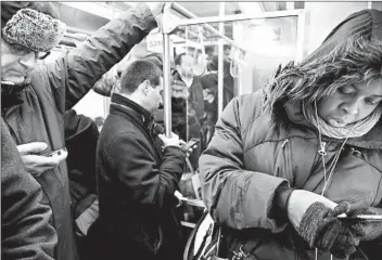  ?? ANTONIO PEREZ/CHICAGO TRIBUNE ?? Commuters interact with their cellphones — and not one another — as they ride a CTA Red Line train.
