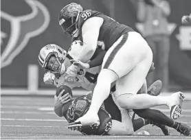 ?? ?? Saints quarterbac­k Derek Carr (4) is sacked by Texans defensive tackle Maliek Collins (96) and defensive end Jonathan Greenard (52) in the second half in Houston on Sunday.