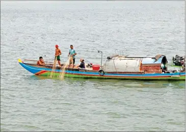  ?? HENG CHIVOAN ?? A family cast their nets for fish on the Mekong River on May 25.