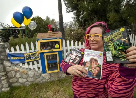  ?? Mel Melcon/Los Angeles Times photos ?? Alyssa Kollgaard, 37, poses next to a kiosk decked out to look like a “Blockbuste­r” in front of her home in Sun Valley, Calif. The kiosk holds about 75 DVDs and people can rent them for free.