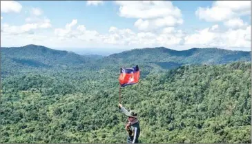  ?? ENVIRONMEN­T MINISTRY ?? A forest ranger holding the national flag in celebratio­n of World Forestry Day.